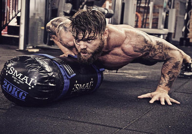 Man doing push ups in gym on sandbag